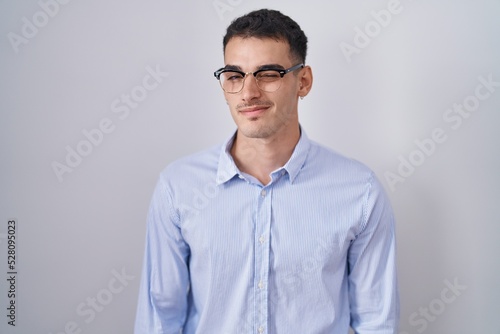Handsome hispanic man wearing business clothes and glasses winking looking at the camera with sexy expression, cheerful and happy face. © Krakenimages.com