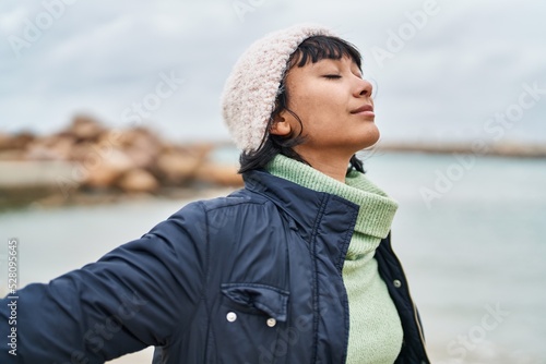 Young beautiful hispanic woman breathing with arms open at seaside © Krakenimages.com