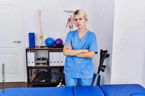 Young physiotherapist woman working at pain recovery clinic skeptic and nervous  disapproving expression on face with crossed arms. negative person.