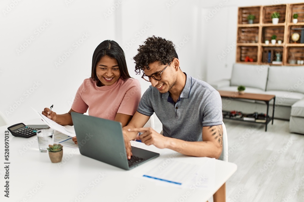 Young latin couple working using laptop sitting on the table at home. Young latin couple working using laptop sitting on the table at home.