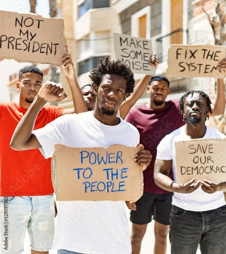 Billede på lærred Group of young african american activists holding protest banner protesting at the city