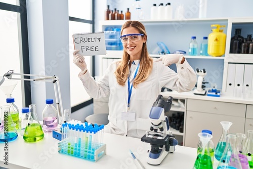 Young blonde scientist woman working on cruelty free laboratory pointing finger to one self smiling happy and proud