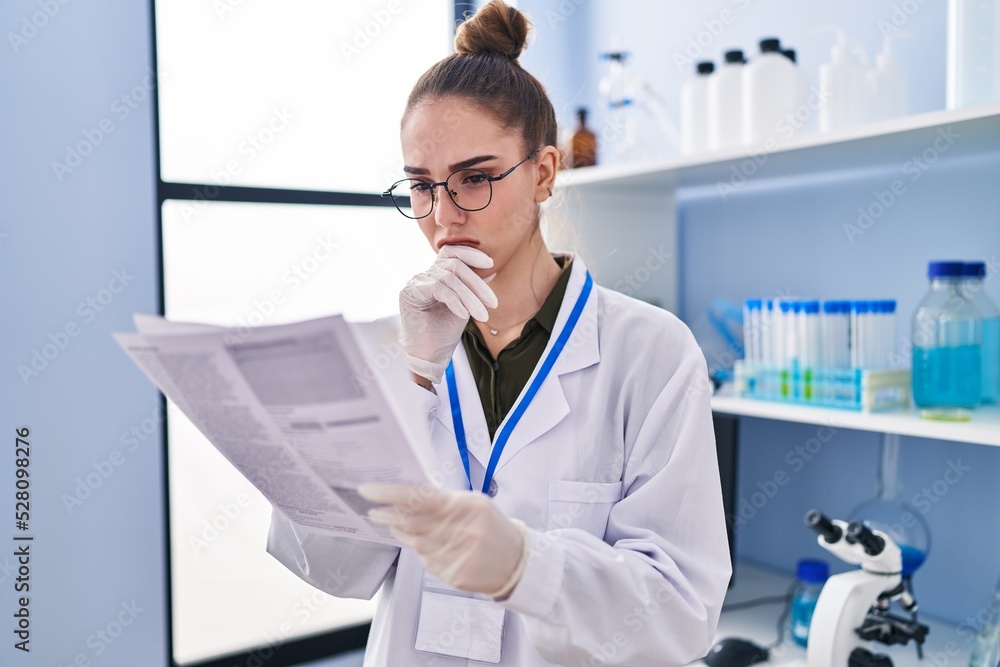 Young woman scientist reading document at laboratory Young woman scientist reading document at laboratory
