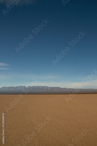 View of the arid desert in Barreal Blanco, in San Juan, Argentina. The Andes mountains in the horizon under a deep blue sky.
