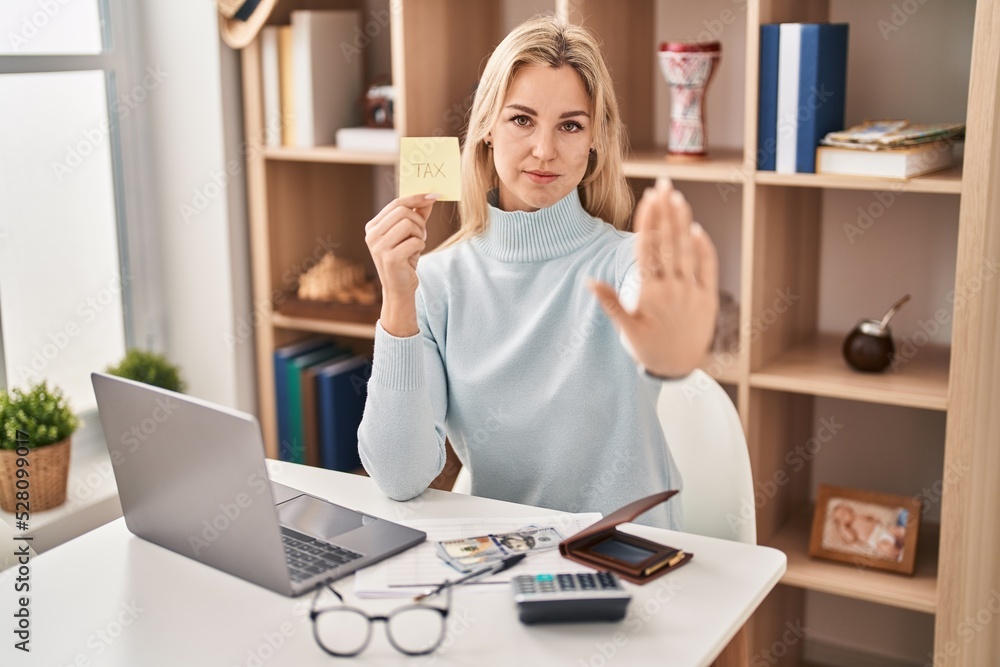Young caucasian woman calculating money savings with open hand doing stop sign with serious and confident expression, defense gesture Young caucasian woman calculating money savings with open hand doing stop sign with serious and confident expression, defense gesture