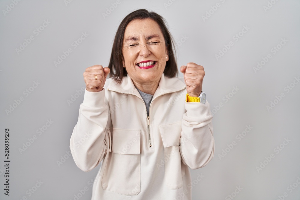 Middle age hispanic woman standing over isolated background excited for success with arms raised and eyes closed celebrating victory smiling. winner concept. Middle age hispanic woman standing over isolated background excited for success with arms raised and eyes closed celebrating victory smiling. winner concept.