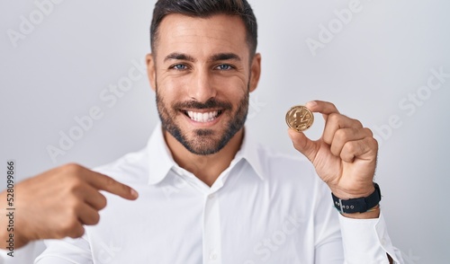 Handsome hispanic man holding litecoin cryptocurrency coin pointing finger to one self smiling happy and proud © Krakenimages.com