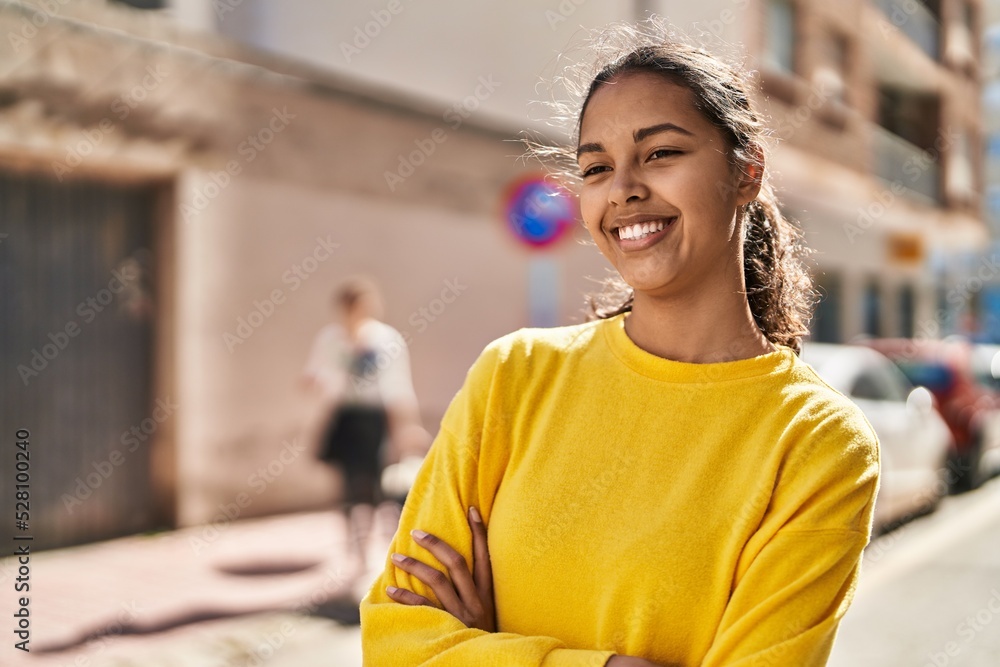 Naklejka premium Young african american woman smiling confident standing with arms crossed gesture at street