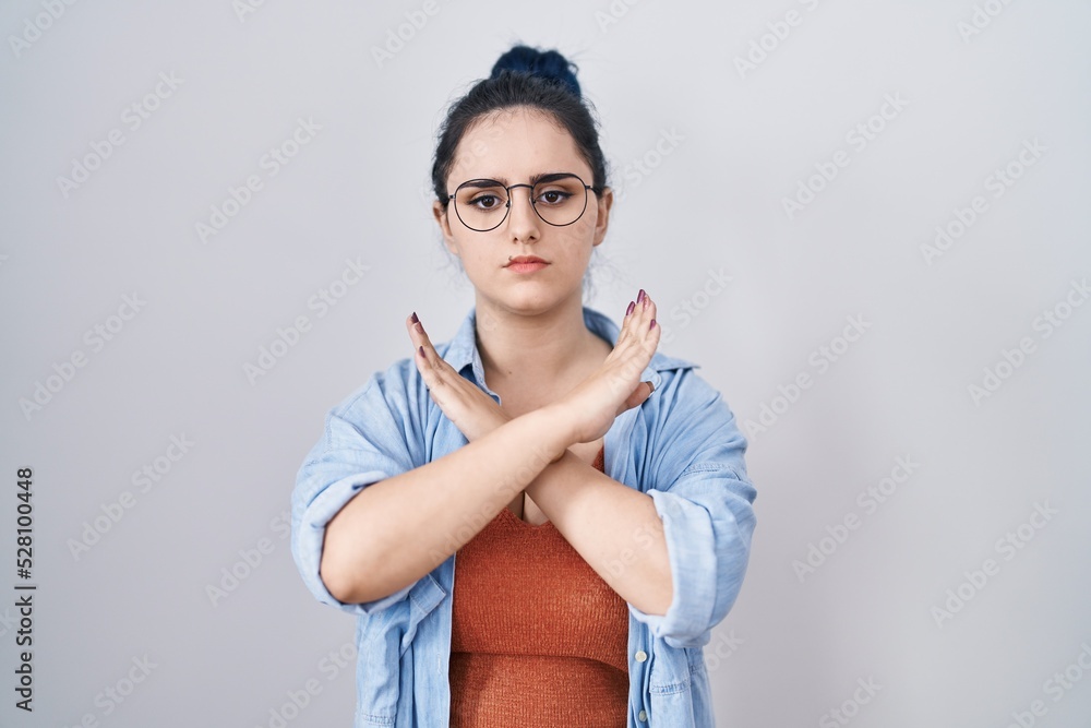 Young modern girl with blue hair standing over white background rejection expression crossing arms doing negative sign, angry face
