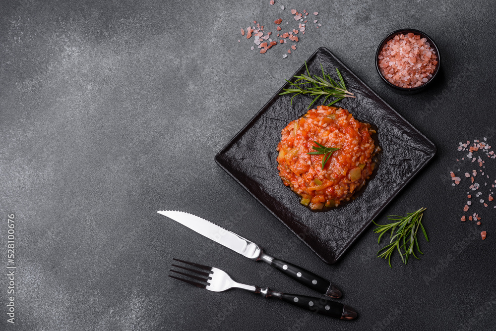 Boiled rice with peppers, spices, herbs and tomato sauce on a black slate plate Boiled rice with peppers, spices, herbs and tomato sauce on a black slate plate
