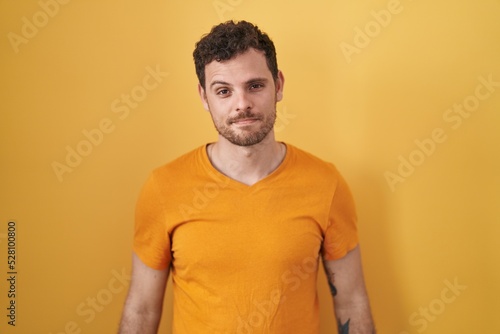 Young hispanic man standing over yellow background looking sleepy and tired, exhausted for fatigue and hangover, lazy eyes in the morning. © Krakenimages.com