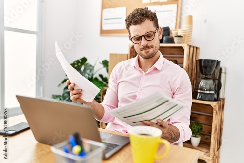 Young hispanic man reading document working at office