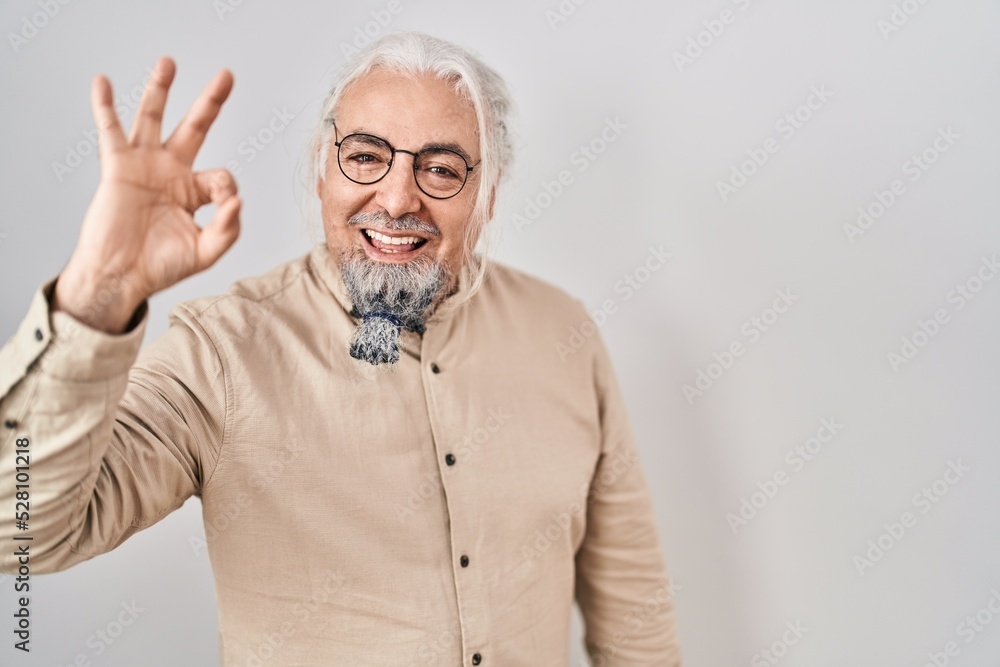 Middle age man with grey hair standing over isolated background smiling positive doing ok sign with hand and fingers. successful expression. Middle age man with grey hair standing over isolated background smiling positive doing ok sign with hand and fingers. successful expression.