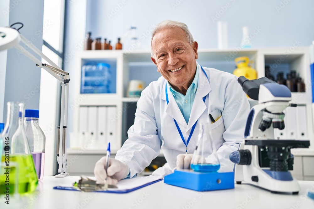 Senior man wearing scientist uniform measuring liquid at laboratory