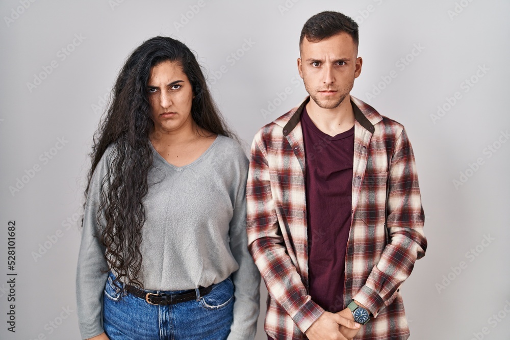 Young hispanic couple standing over white background skeptic and nervous, frowning upset because of problem. negative person. Young hispanic couple standing over white background skeptic and nervous, frowning upset because of problem. negative person.