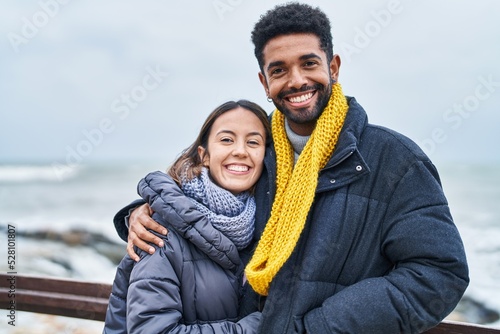 Man and woman couple smiling confident hugging each other at seaside