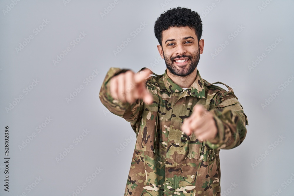 Arab man wearing camouflage army uniform pointing to you and the camera with fingers, smiling positive and cheerful Arab man wearing camouflage army uniform pointing to you and the camera with fingers, smiling positive and cheerful