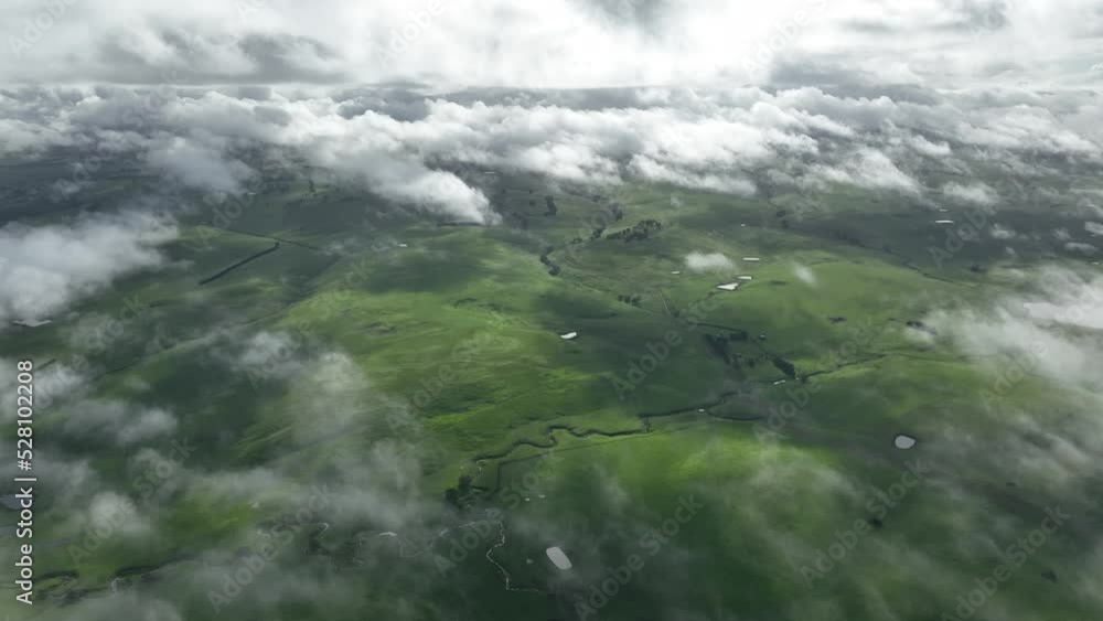 Flying above clouds over hills. above fog on a farm landscape below. mist covering the mountains in the country Flying above clouds over hills. above fog on a farm landscape below. mist covering the mountains in the country