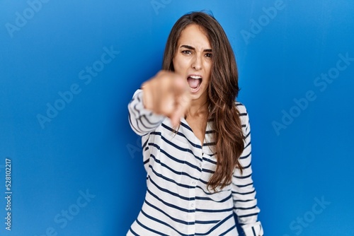 Young hispanic woman standing over blue isolated background pointing displeased and frustrated to the camera, angry and furious with you