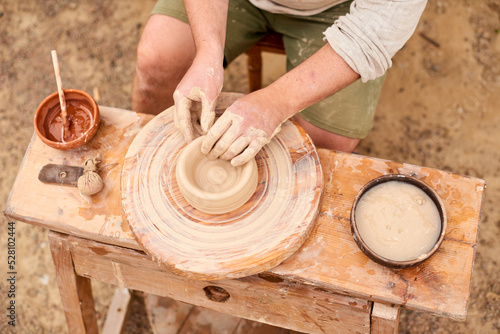 craftsman hands make clay product on mechanical potter's wheel. horizontal top view photo