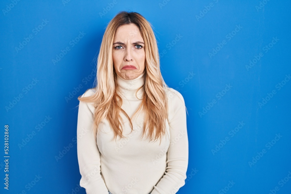 Young caucasian woman standing over blue background depressed and worry for distress, crying angry and afraid. sad expression. Young caucasian woman standing over blue background depressed and worry for distress, crying angry and afraid. sad expression.
