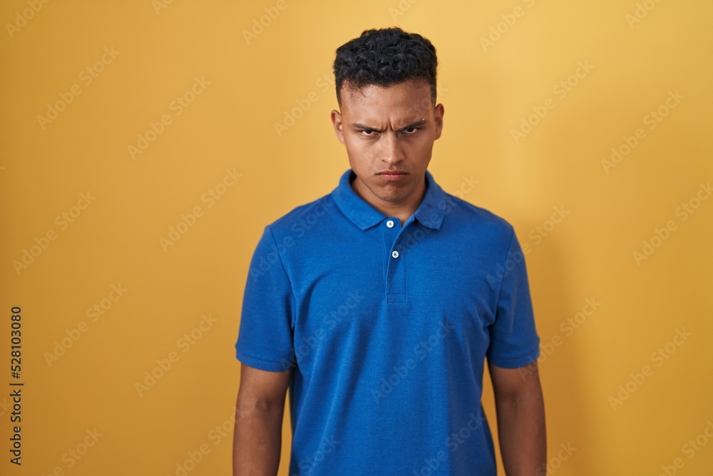 Young hispanic man standing over yellow background skeptic and nervous, frowning upset because of problem. negative person. Young hispanic man standing over yellow background skeptic and nervous, frowning upset because of problem. negative person.