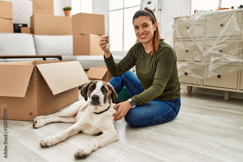 Young woman holding key sitting on floor with dog at home © Krakenimages.com