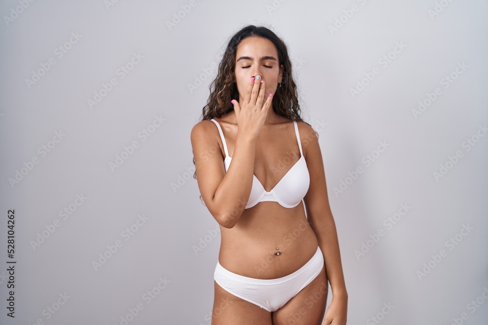 Obraz premium Young hispanic woman wearing white lingerie bored yawning tired covering mouth with hand. restless and sleepiness.