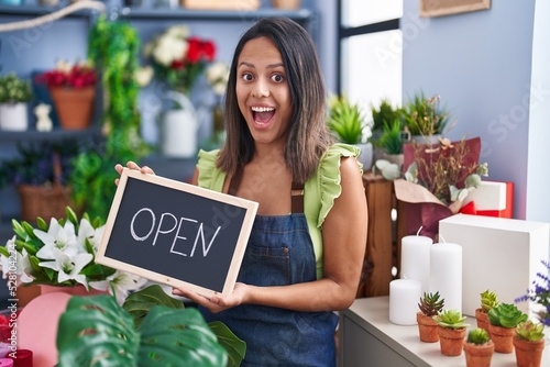 Hispanic young woman working at florist with open sign celebrating crazy and amazed for success with open eyes screaming excited.