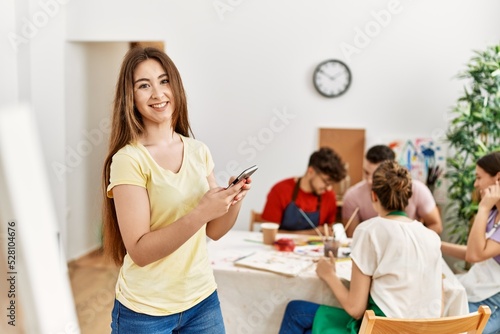 Group of people drawing sitting on the table. Woman smiling happy using smartphone at art studio.