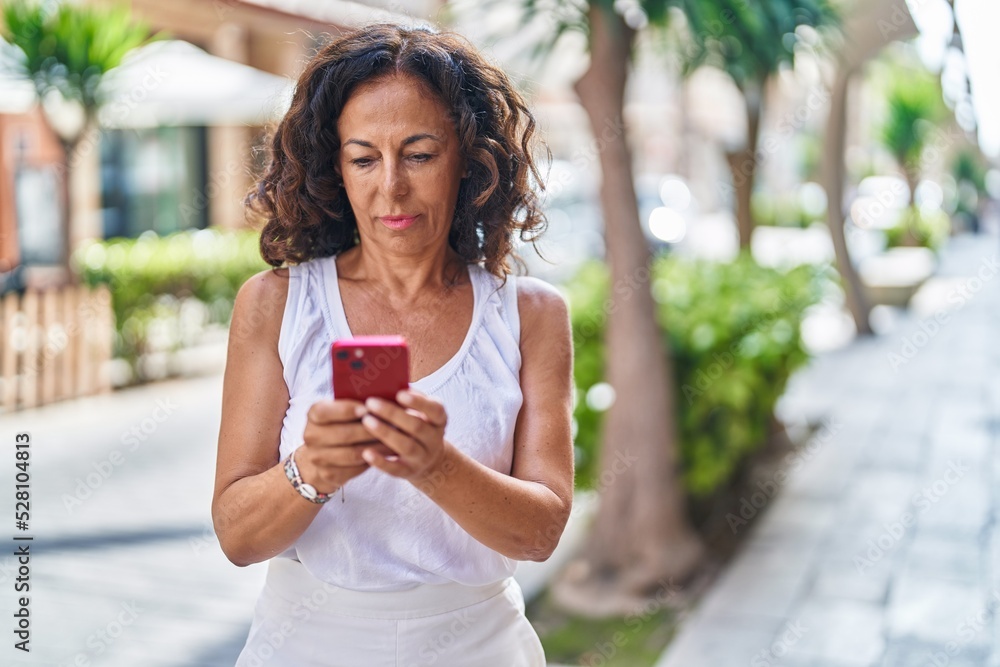 Middle age woman using smartphone with serious expression at street Middle age woman using smartphone with serious expression at street