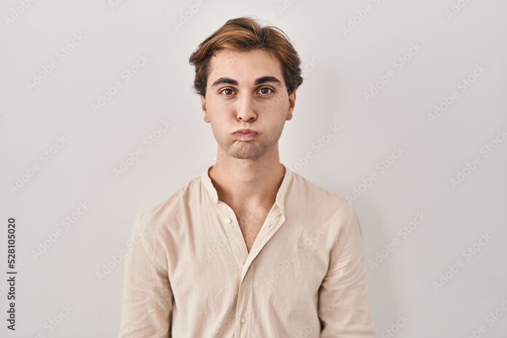 Young man standing over isolated background puffing cheeks with funny face. mouth inflated with air, crazy expression. Young man standing over isolated background puffing cheeks with funny face. mouth inflated with air, crazy expression.