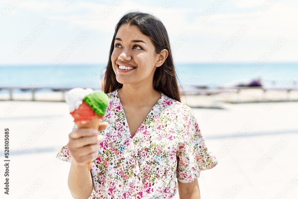Young latin girl smiling happy eating ice cream at the beach. Young latin girl smiling happy eating ice cream at the beach.