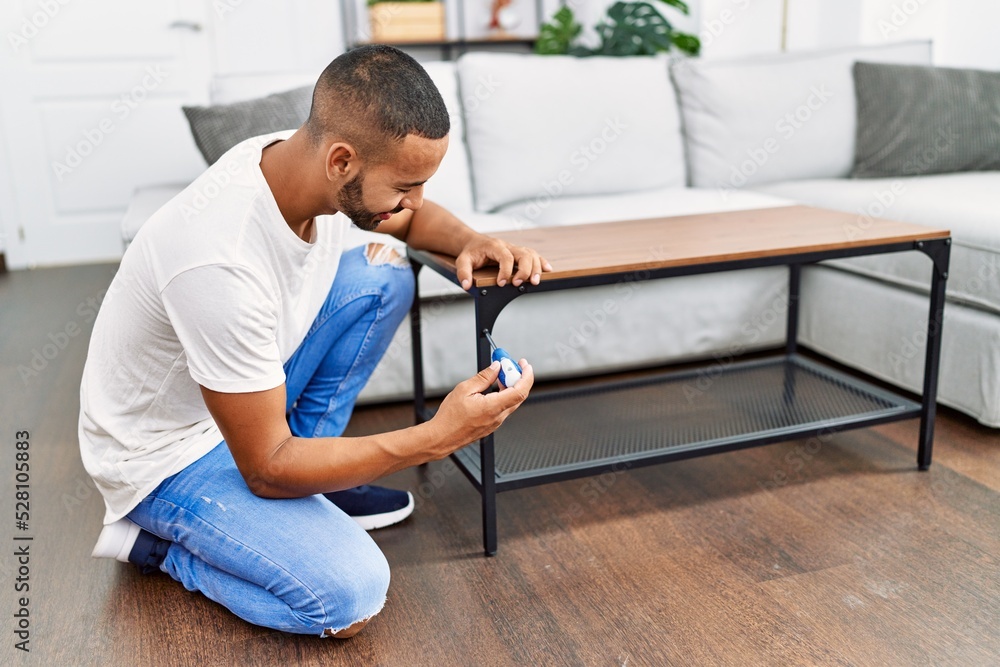 Young hispanic man smiling confident reparing table at home