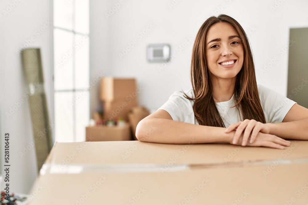 Young hispanic woman smiling confident leaning on package at new home Young hispanic woman smiling confident leaning on package at new home