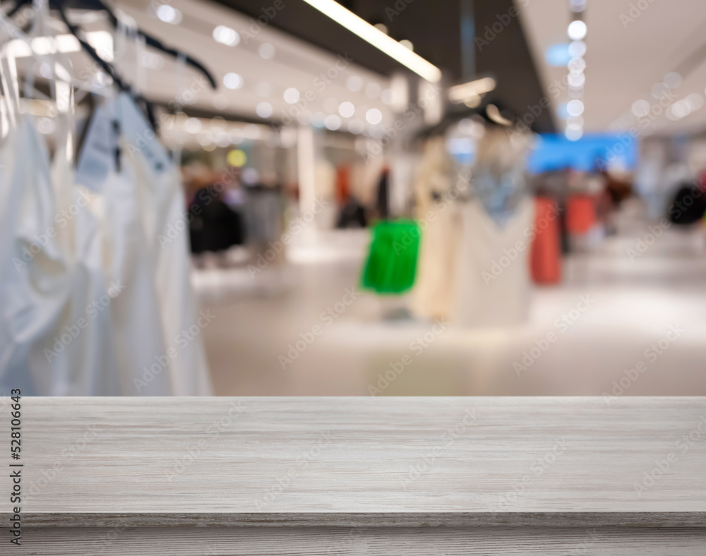 Empty wooden surface and blurred view of clothes store interior. Space for design Empty wooden surface and blurred view of clothes store interior. Space for design