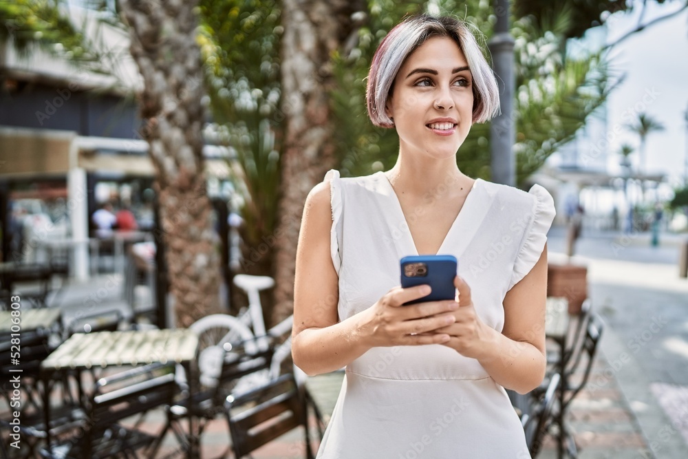 Young caucasian girl smiling happy using smartphone at the city.