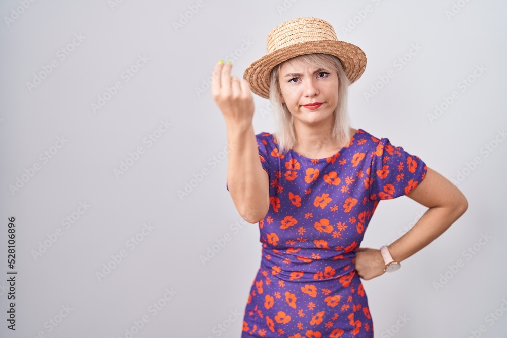 Young caucasian woman wearing flowers dress and summer hat doing italian gesture with hand and fingers confident expression Young caucasian woman wearing flowers dress and summer hat doing italian gesture with hand and fingers confident expression