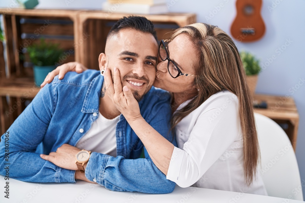 Man and woman mother and son sitting on table kissing at home Man and woman mother and son sitting on table kissing at home