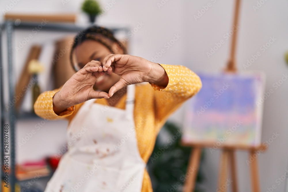 Obraz premium African american woman with braids at art studio smiling in love showing heart symbol and shape with hands. romantic concept.