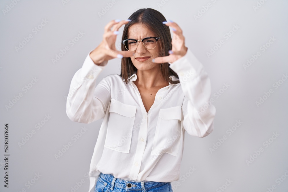 Young brunette woman wearing glasses shouting frustrated with rage, hands trying to strangle, yelling mad Young brunette woman wearing glasses shouting frustrated with rage, hands trying to strangle, yelling mad