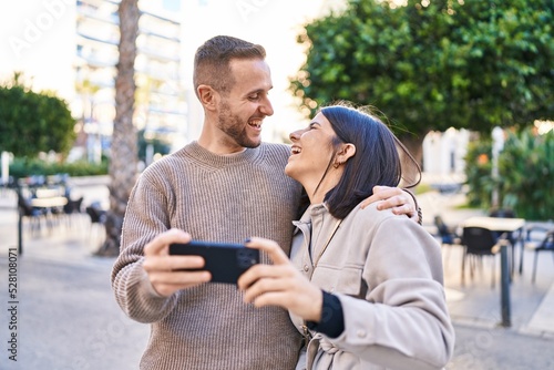 Man and woman couple smiling confident using smartphone at street