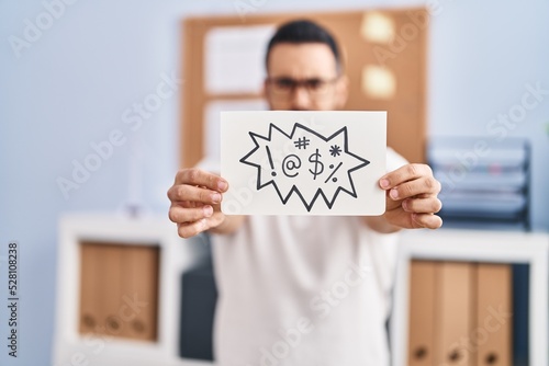 Young hispanic man business worker holding onomatopeia shout message at office