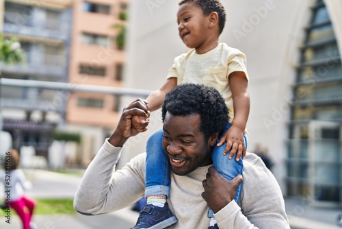 Father and son holding boy on shoulders at playground