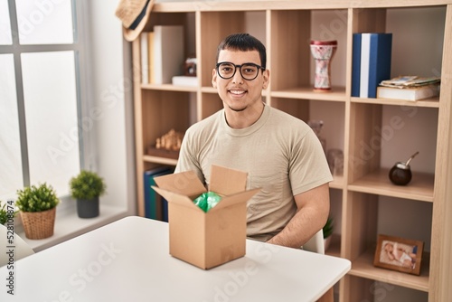 Young arab man with open gift in cardboard box with a happy and cool smile on face. lucky person.