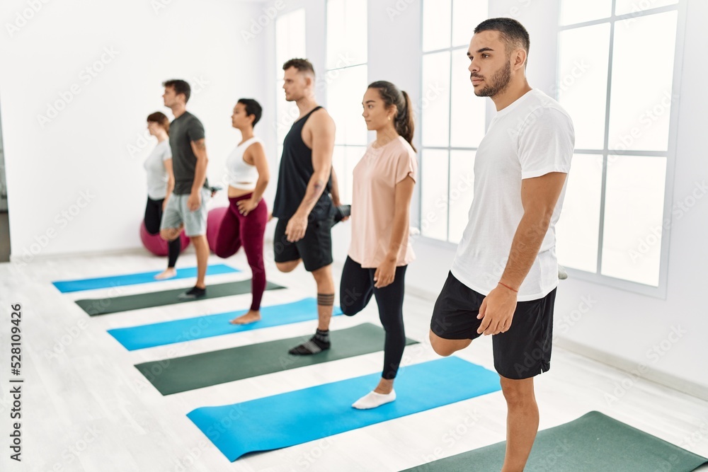 Naklejka premium Group of young hispanic people concentrate stretching at sport center.