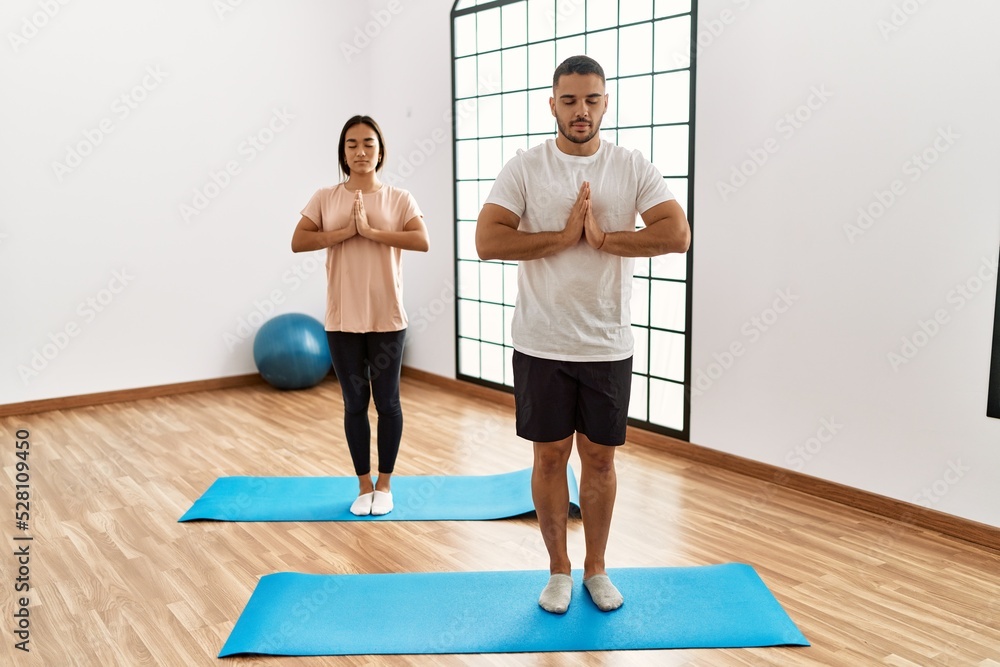 Latin man and woman couple training yoga at sport center