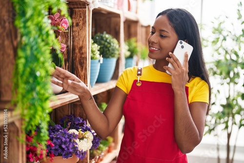 Young beautiful woman florist talking on smartphone at florist