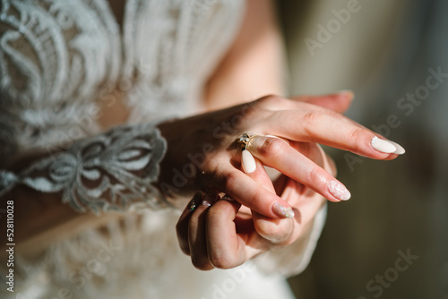 The bride wears or adjusts the diamond ring. Close hands.