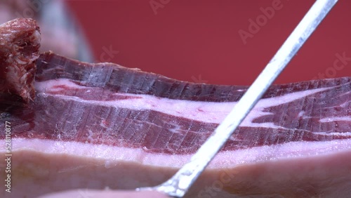 Detalle de las manos de un maestro jamonero cortando tacos de jamón. 